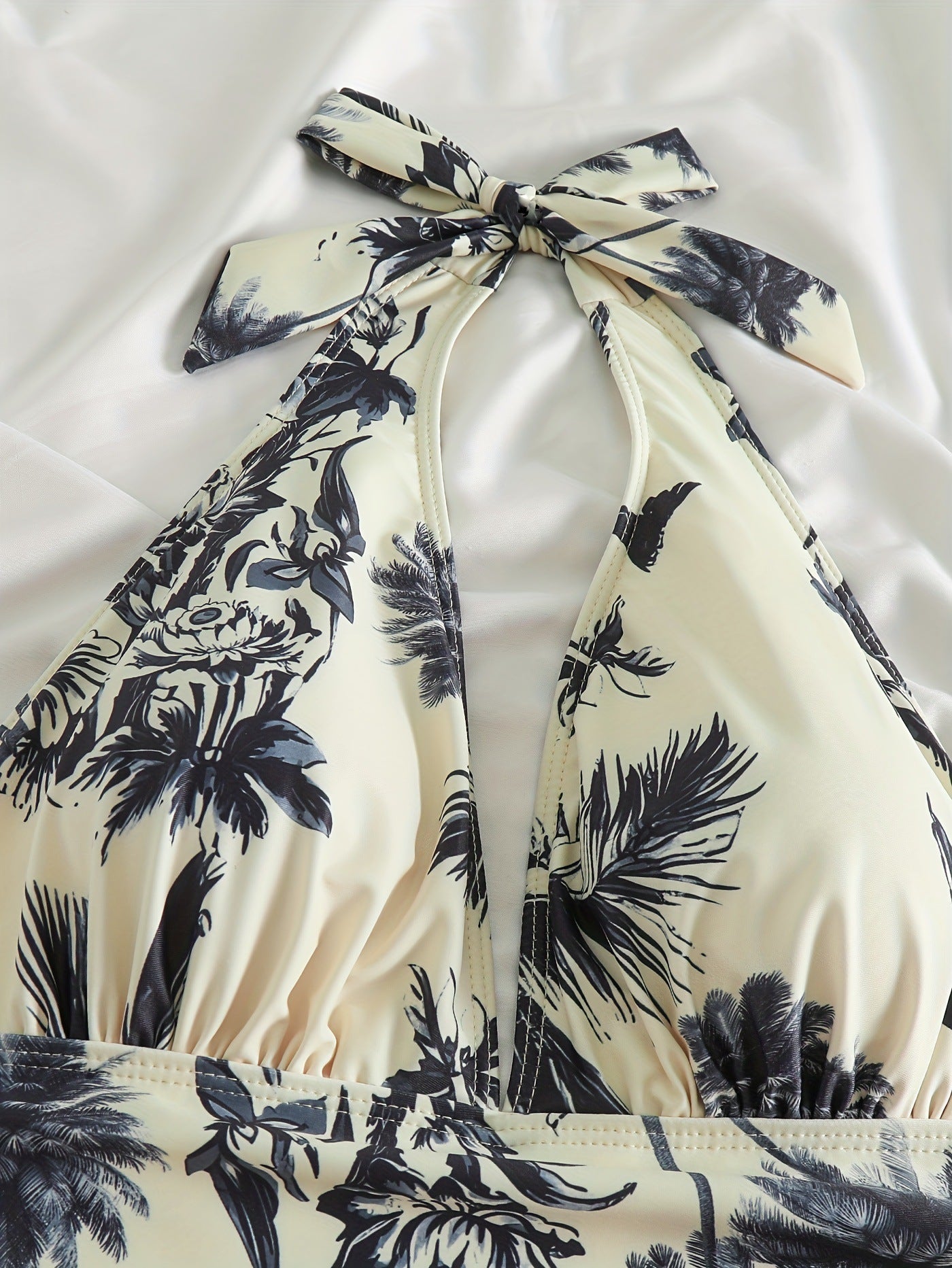 Close-up of halter top swimsuit neckline with tropical leaf print and gathered bust detail