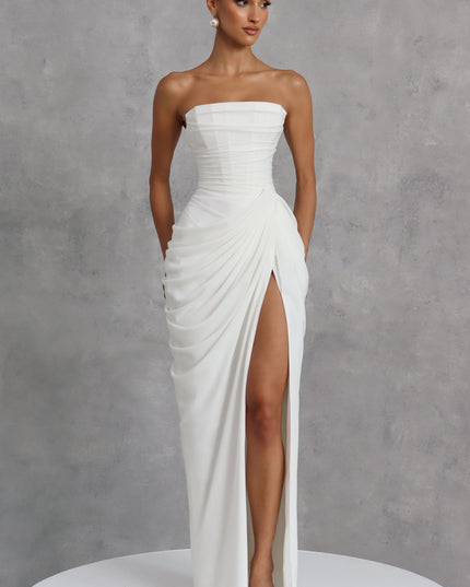 White strapless corset womens dress on gray backdrop, ruched waist and thigh split maxi skirt