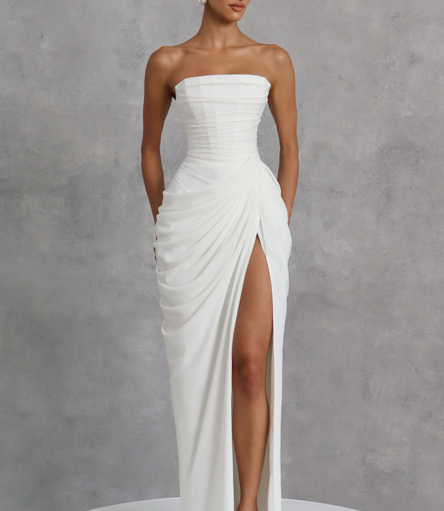 White strapless corset womens dress on gray backdrop, ruched waist and thigh split maxi skirt
