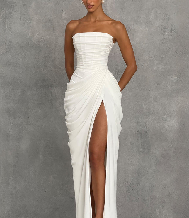 Angled view of white strapless corset maxi womens dress with pleated drape and thigh split skirt