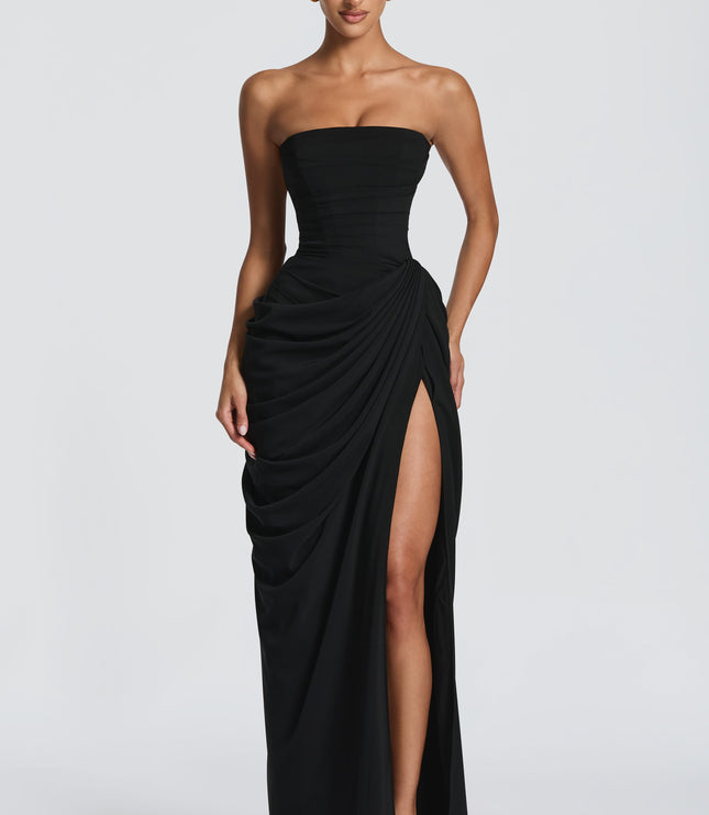 Back view of black strapless corset dress with lace-up detail and draped maxi skirt