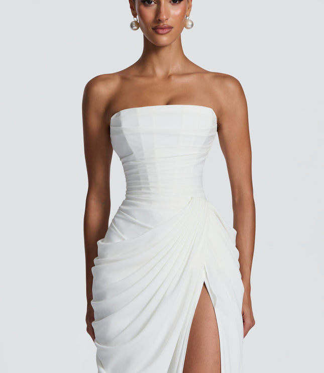 Close-up white strapless corset top and ruched draped skirt detail on maxi dress with thigh split