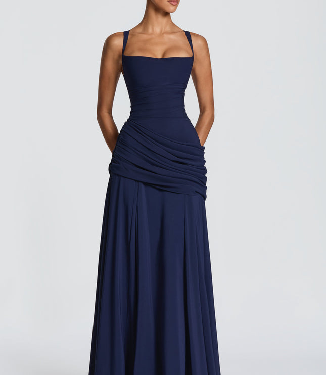 Full length navy blue square neck maxi dress with draped overlay and flared skirt, angled pose