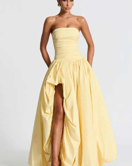 Full length pale yellow strapless high low maxi dress with voluminous skirt and front slit