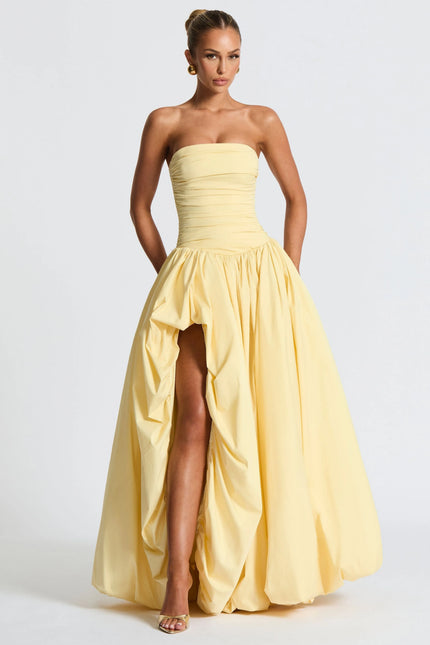 Full length pale yellow strapless high low maxi dress with voluminous skirt and front slit