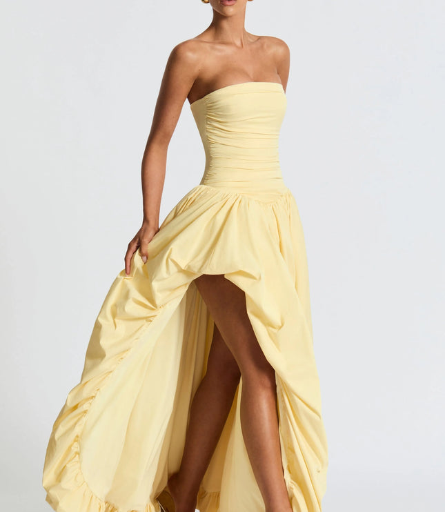 Three-quarter view pale yellow strapless high low maxi cocktail dress with dramatic draped skirt