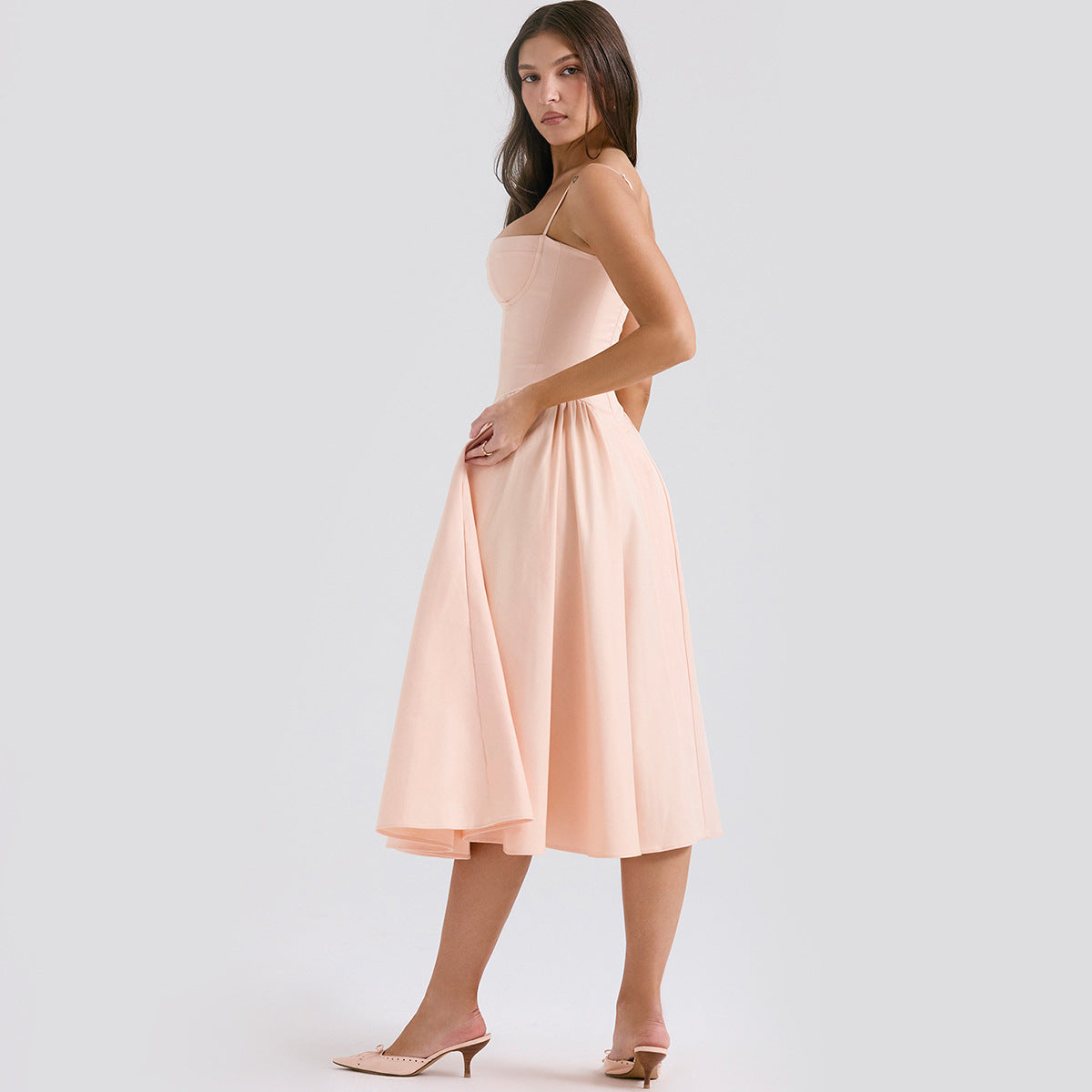 Side view of blush midi dress with adjustable straps, fitted waist, and flared skirt