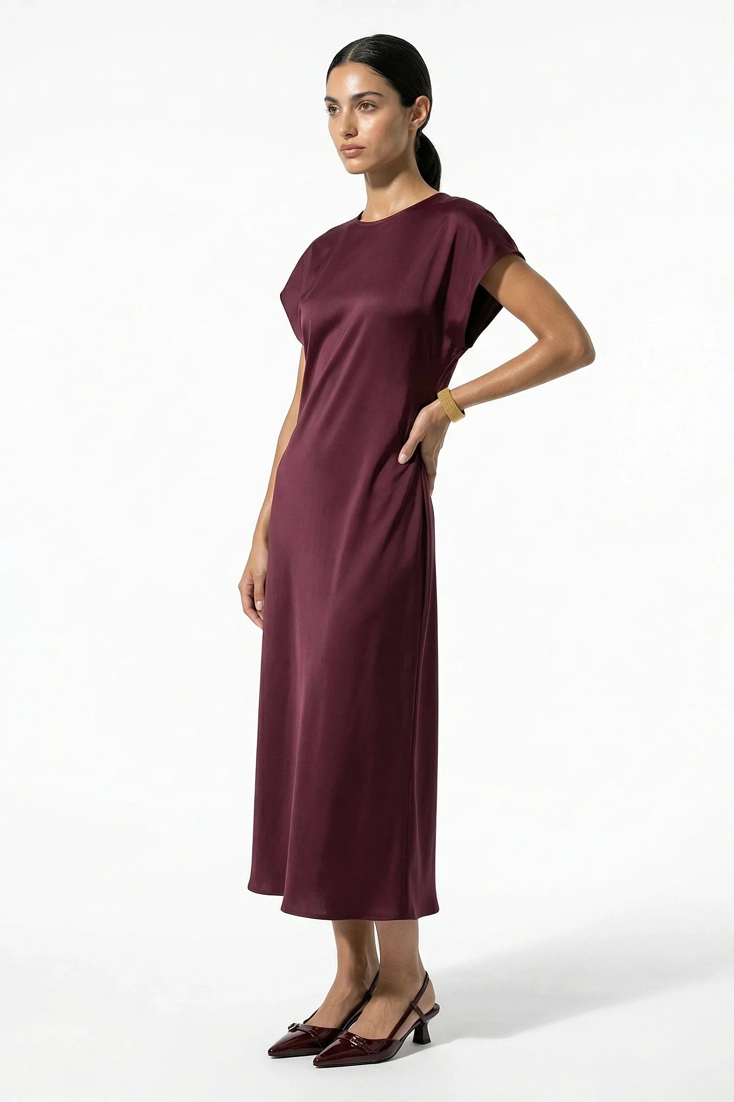 Side view of burgundy satin midi dress with midi length and soft drape