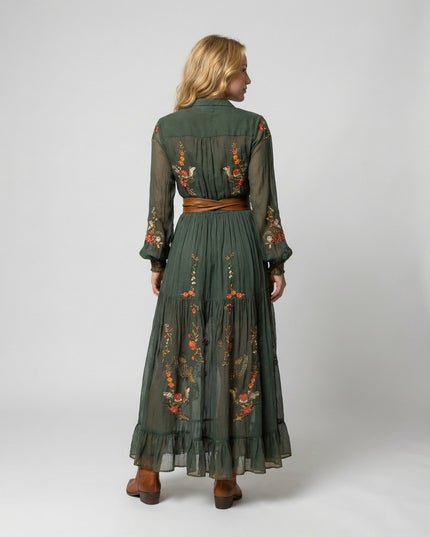 Back view of green floral maxi dress with long sheer sleeves, pleated skirt, and waist belt