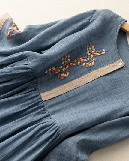 Close-up of blue embroidered midi dress with floral chest stitching and gathered waist