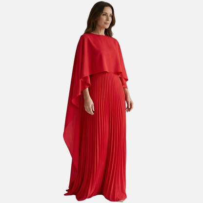 Side view of red formal maxi dress with flowing cape overlay and pleated skirt