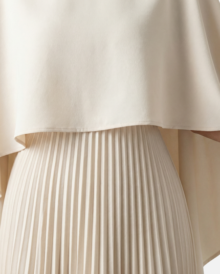 Close-up of beige cape overlay maxi dress showing smooth fabric and pleated skirt detail
