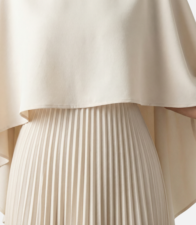 Close-up of beige cape overlay maxi dress showing smooth fabric and pleated skirt detail
