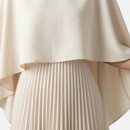 Close-up of beige cape overlay maxi dress showing smooth fabric and pleated skirt detail