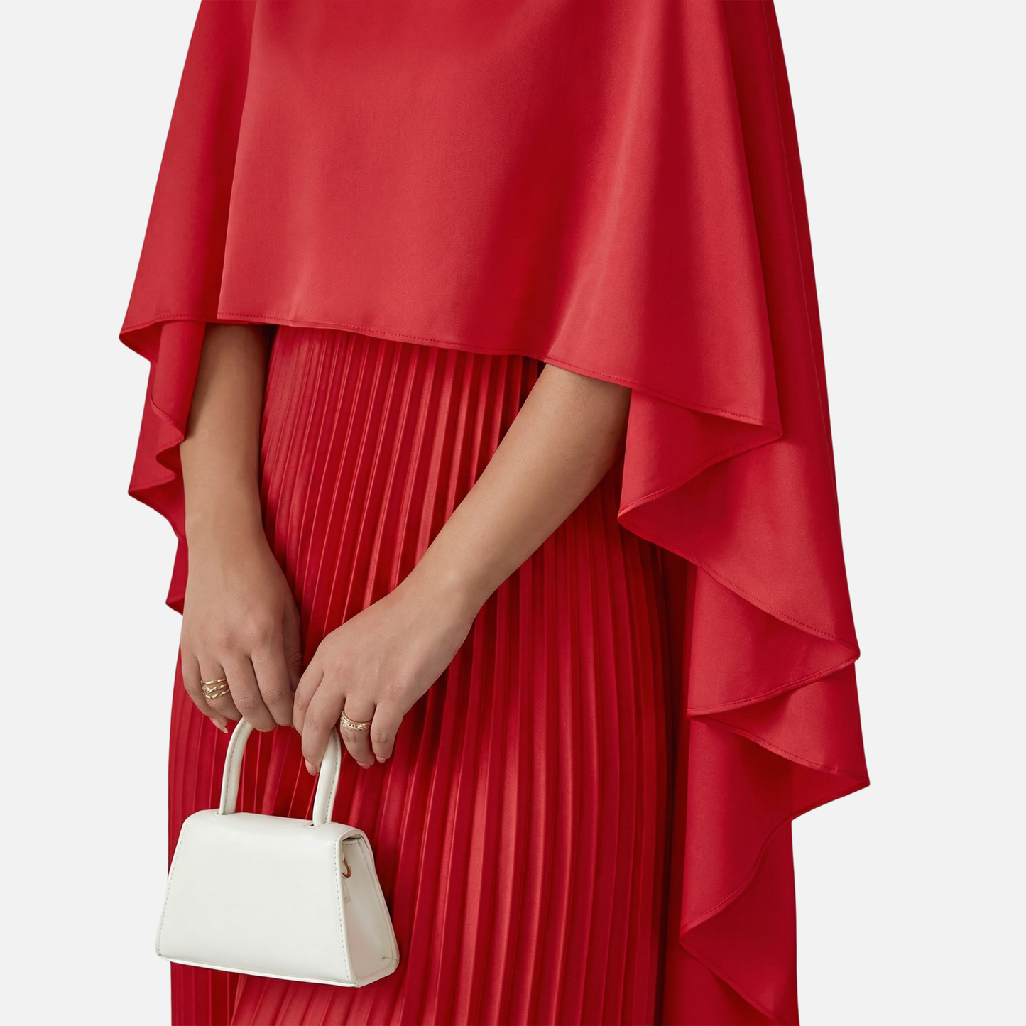 Close-up of red formal maxi dress with cape overlay and vertical pleats on the skirt