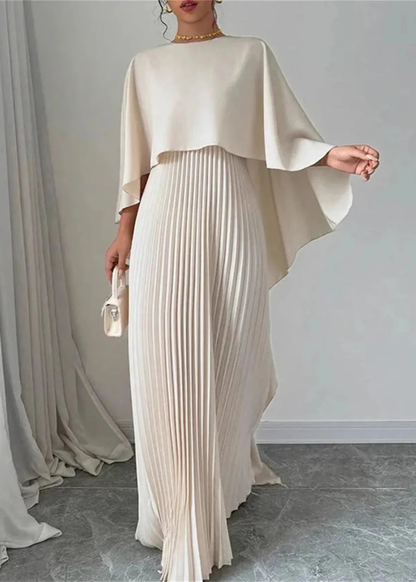 Full-length cream women's formal maxi dress with cape overlay and pleated skirt indoors