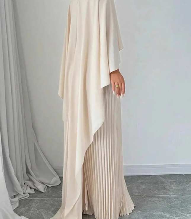 Back view of cream cape overlay maxi dress with flowing drape and pleated skirt