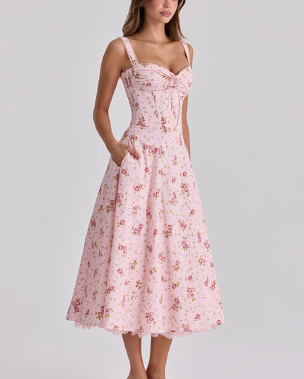 Three-quarter front view of pink floral wedding guest dress with fitted waist and midi length
