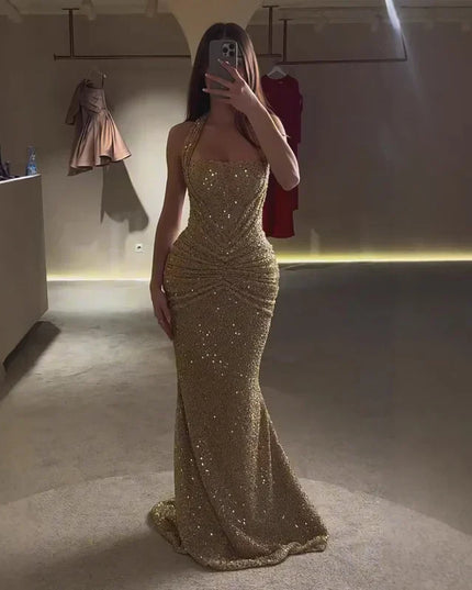 Gold sequin halter maxi dress full length in low light, ruched waist and flared hem