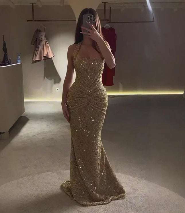 Gold sequin halter maxi dress full length in low light, ruched waist and flared hem