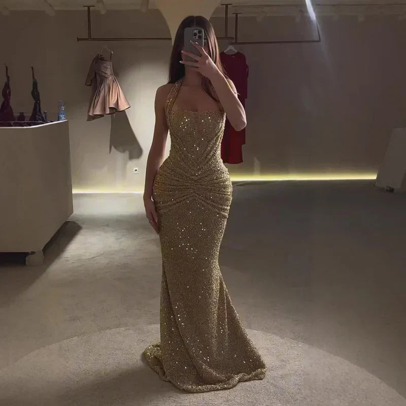 Gold sequin halter maxi dress full length in low light, ruched waist and flared hem