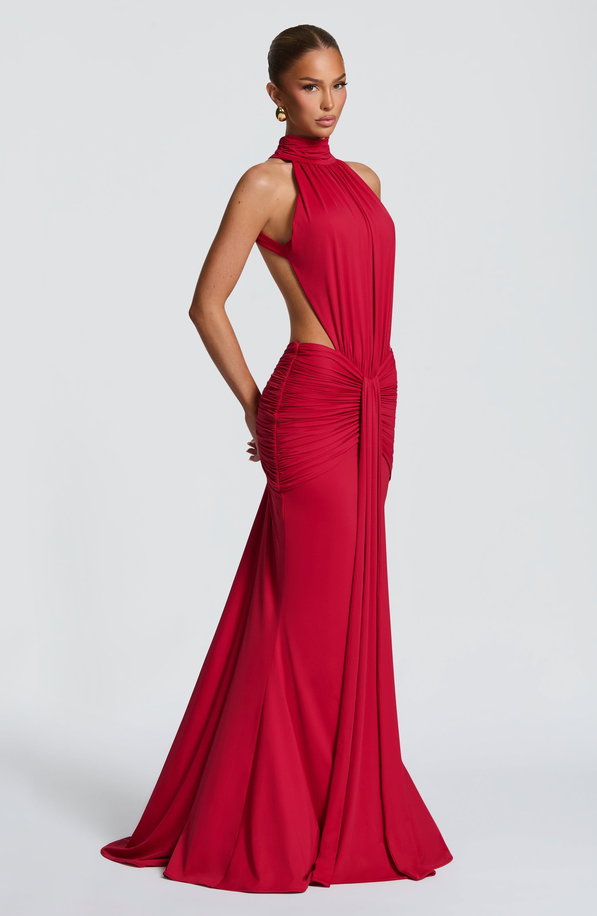 Side view of a red formal halter maxi dress showing ruched waist and flowing skirt