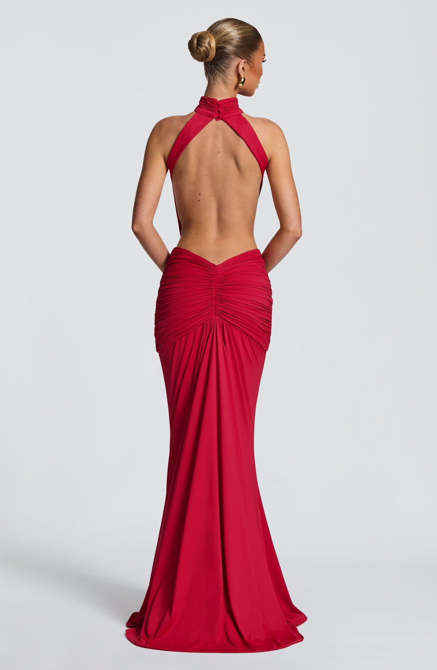 Back view of a red backless maxi dress with halter straps and gathered skirt detail