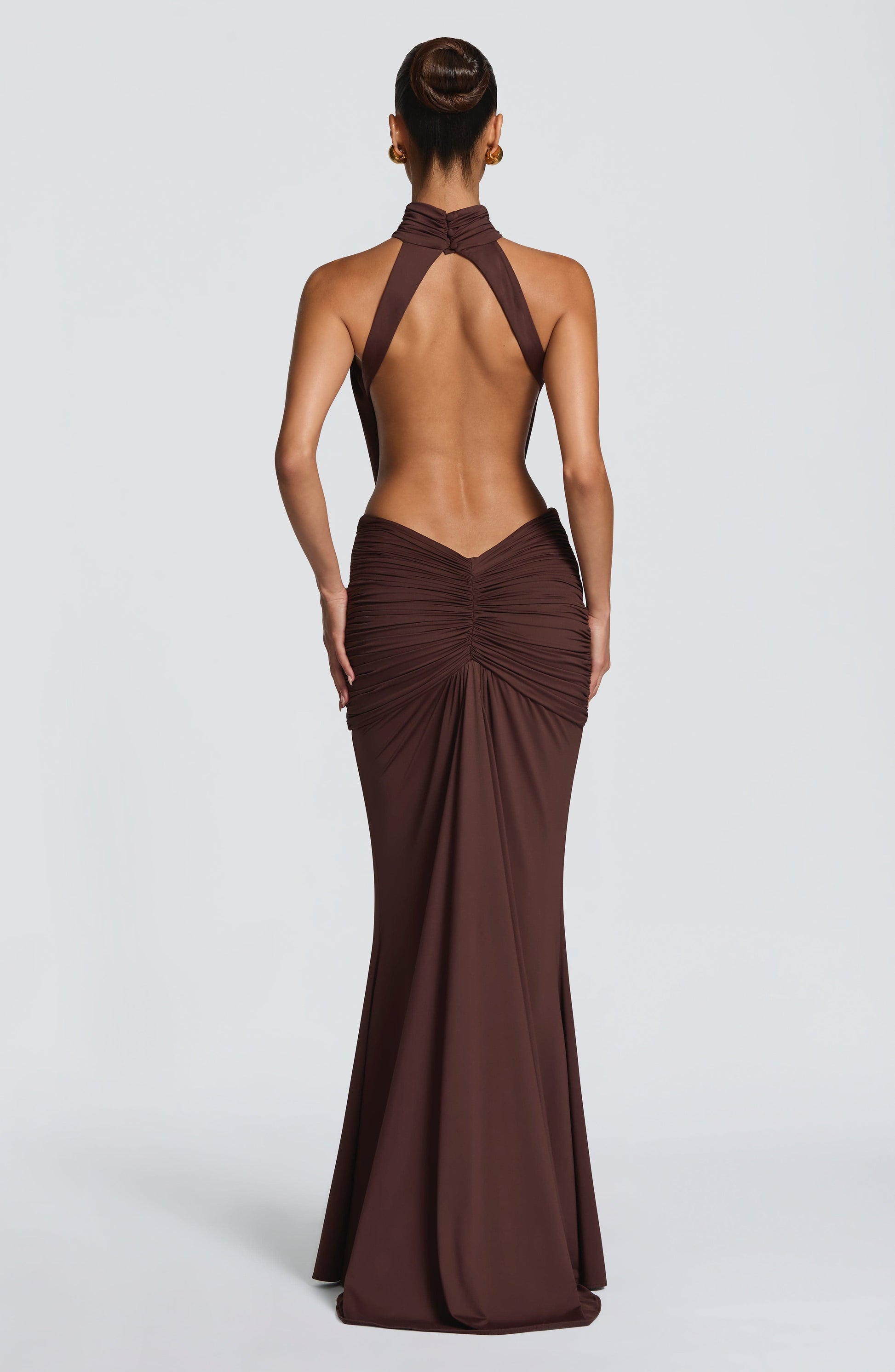 Side view of brown halter maxi dress with draped bodice and floor-length skirt