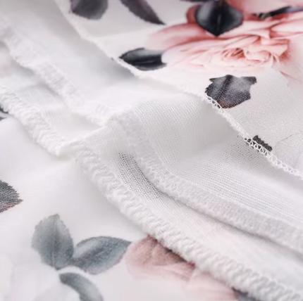 Close-up of floral dress fabric showing sheer hem stitching and printed floral detail