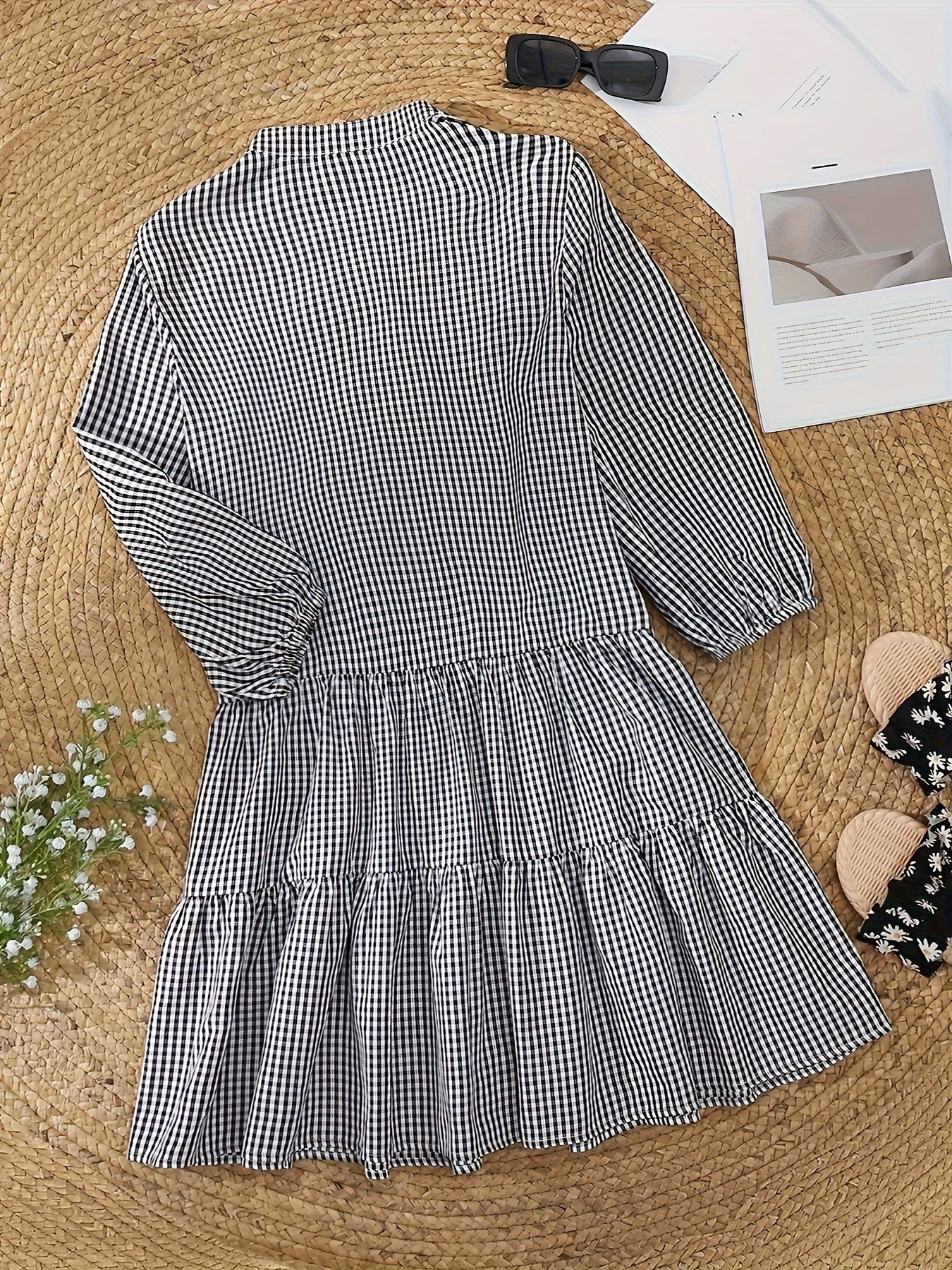 Black and white gingham mini dress laid flat, showing long sleeves and tiered hem