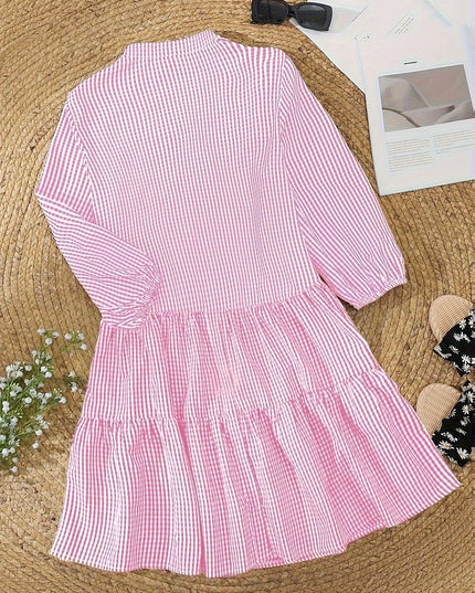 Pink gingham mini dress laid flat, showing V neck, button front, and tiered skirt