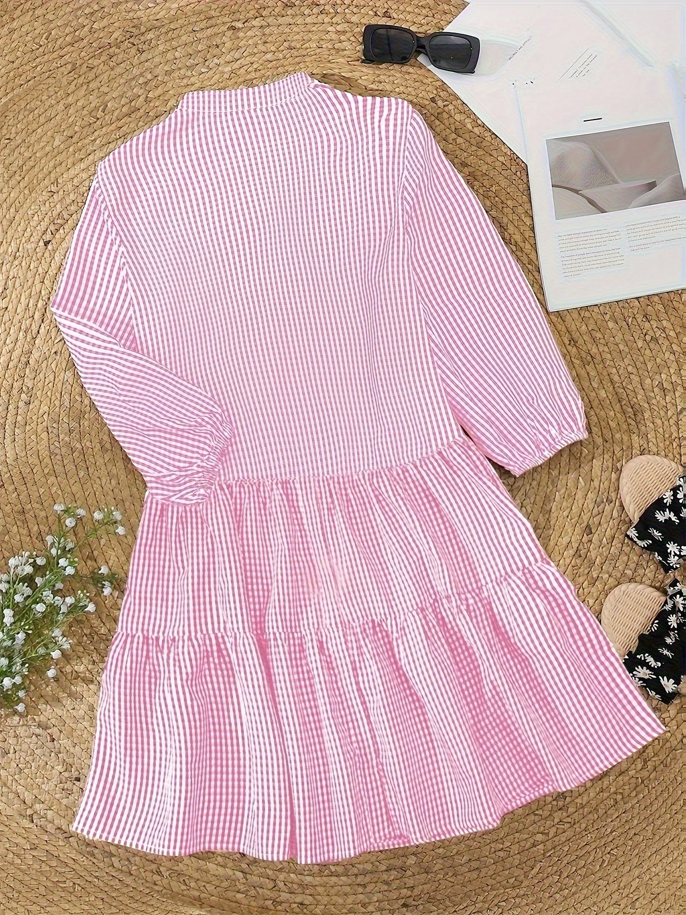 Pink gingham mini dress laid flat, showing V neck, button front, and tiered skirt
