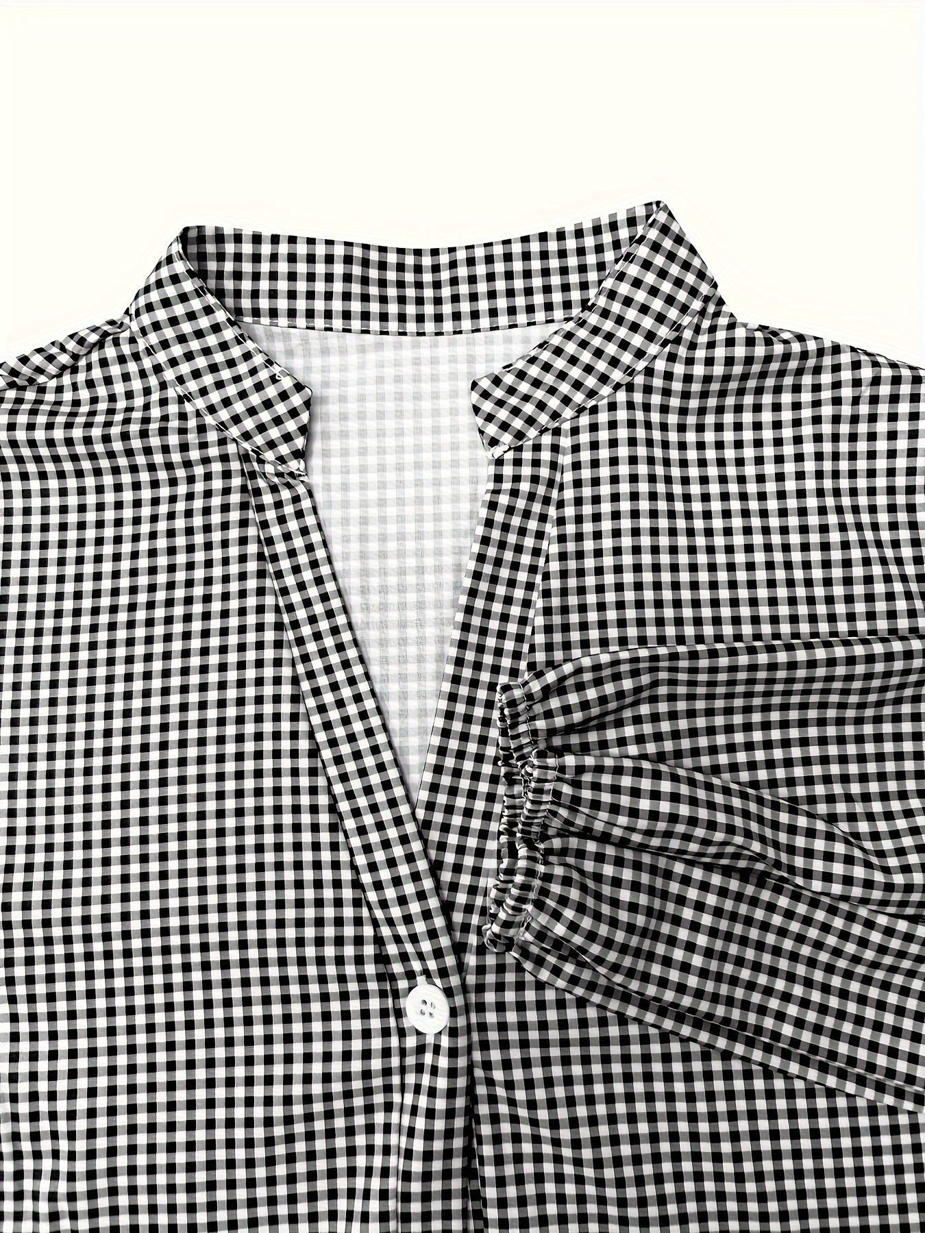 Close-up of black gingham V neck mini dress with collar, button front, and sleeve cuff