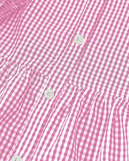 Close-up of pink gingham mini dress fabric with buttons and tiered seam detail