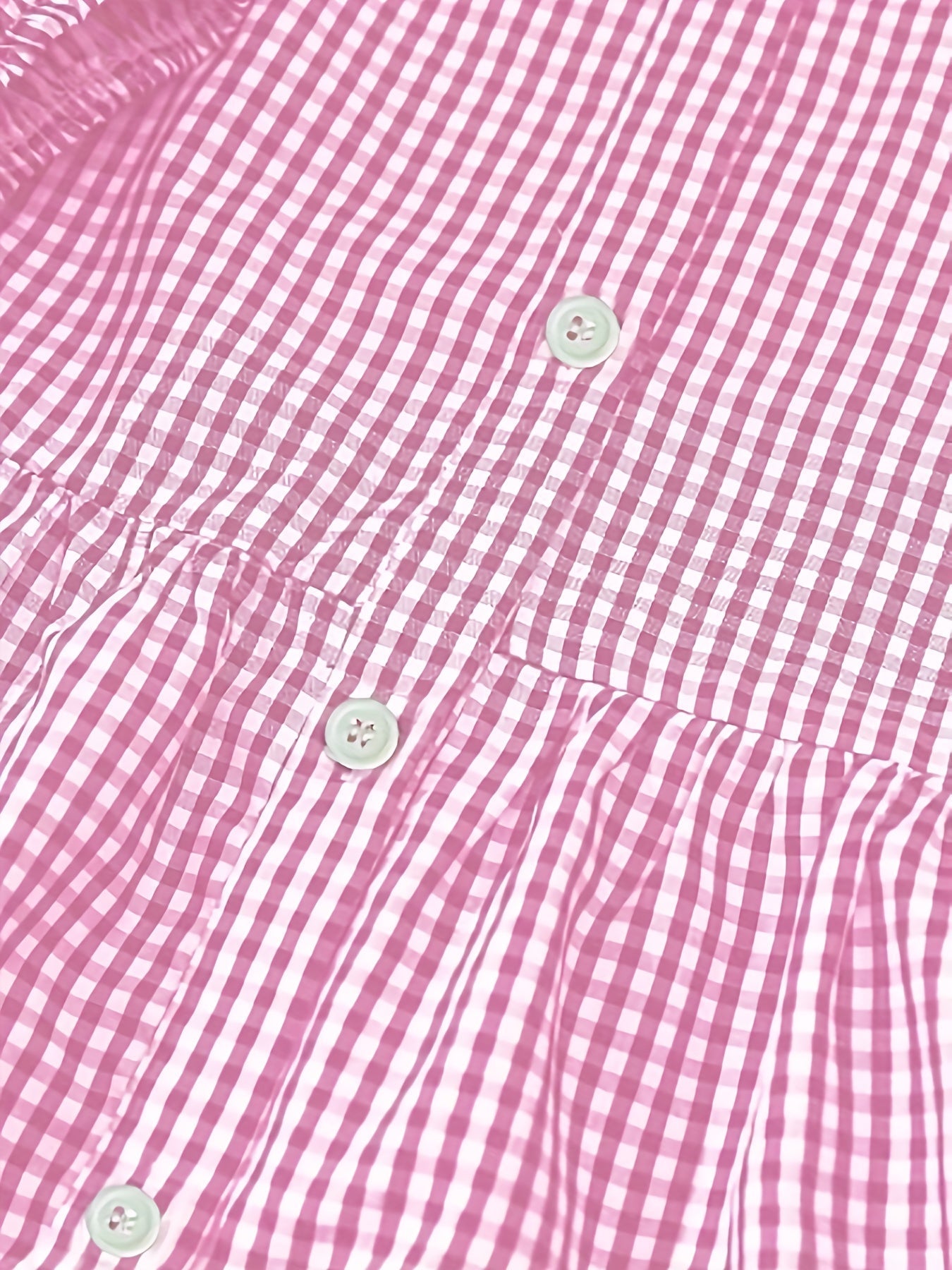 Close-up of pink gingham mini dress fabric with buttons and tiered seam detail