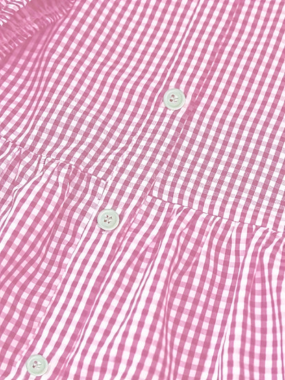 Close-up of pink gingham mini dress fabric with buttons and tiered seam detail