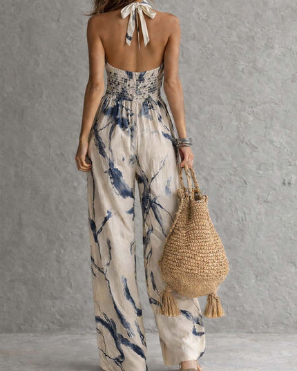 Back view of cream navy printed halter jumpsuit with smocked waist and wide leg pants