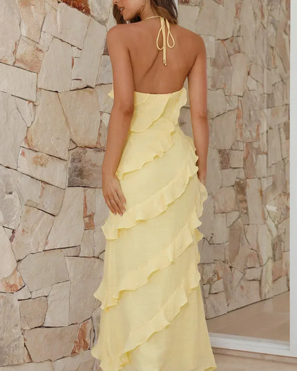 Back view of pale yellow maxi dress with open back and ruffle layers, styled with heeled sandals