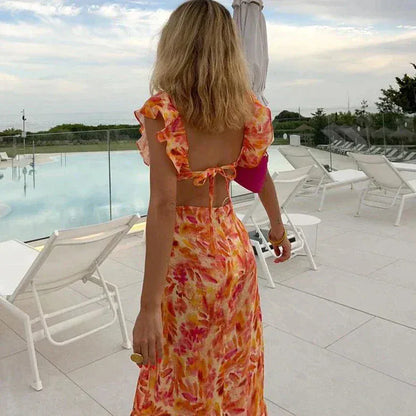 Back view of floral ruffle maxi dress with open back tie detail and flutter sleeves