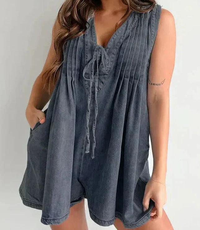Dark washed mini denim romper for women with V-neck tie front, pleated bodice, and relaxed shorts