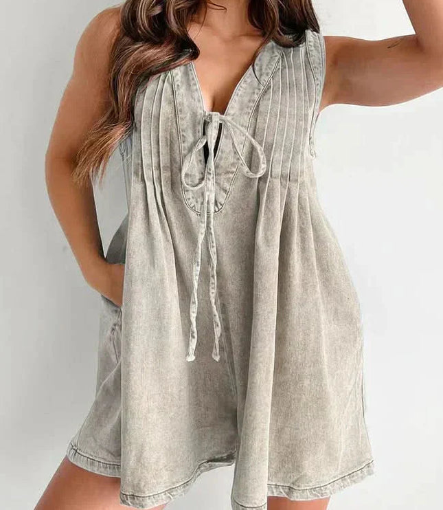 Beige washed casual mini denim romper with pleated front, tie neckline, and sleeveless summer style