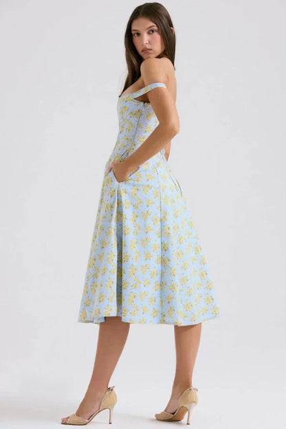 Three-quarter back view of a blue floral midi dress with off shoulder sleeves and slit