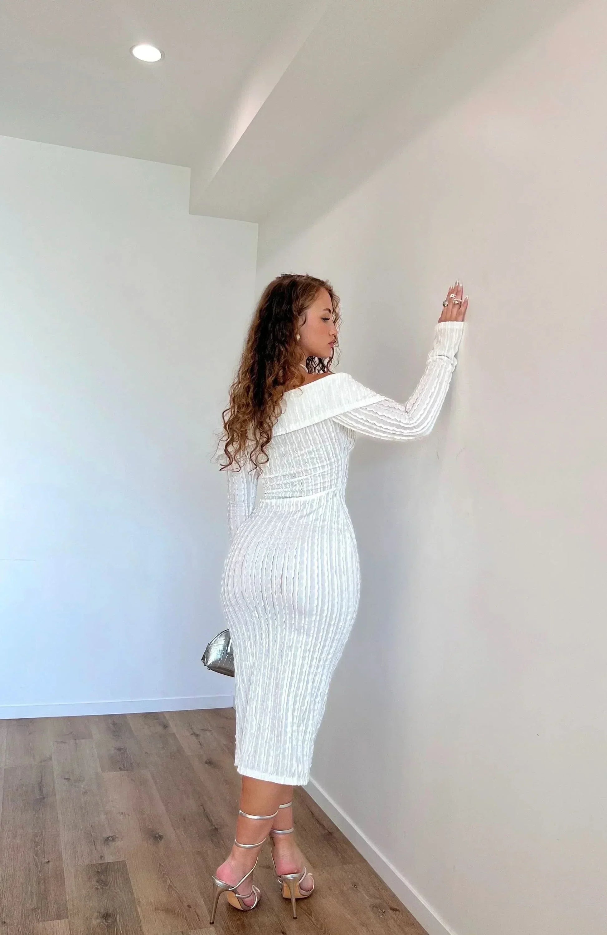 Back view of white off shoulder long sleeve midi dress with fitted ribbed fabric