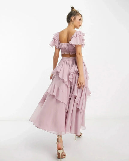 Side view of blush pink midi dress showing off-shoulder ruffles and cascading layered skirt