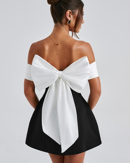 Back view of black cocktail mini dress with oversized white bow and off shoulder sleeves