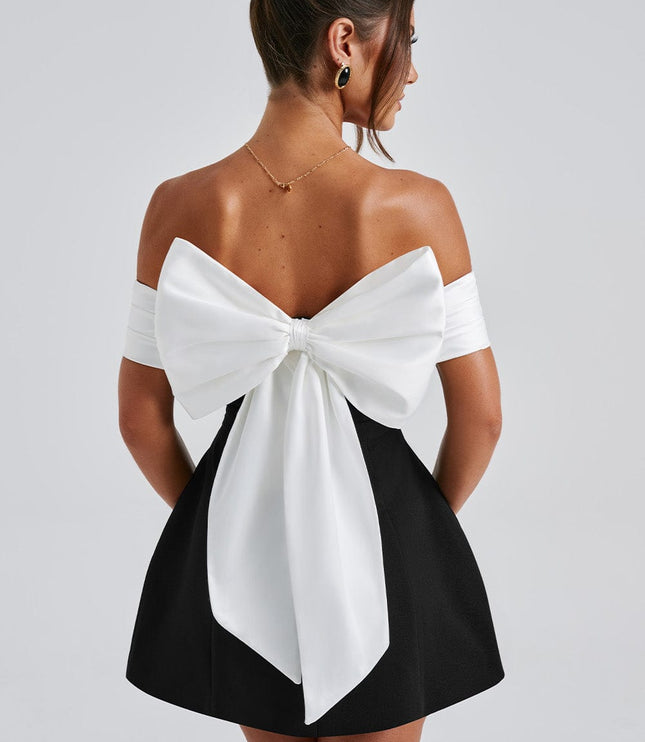 Back view of black cocktail mini dress with oversized white bow and off shoulder sleeves