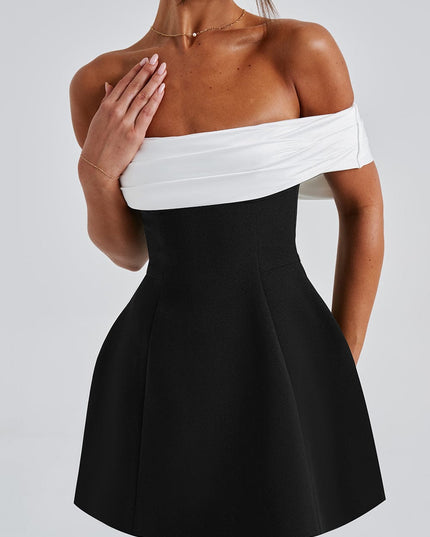 Close front view of black mini dress showing white off shoulder wrap detail and fitted waist
