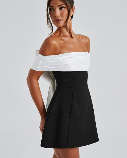 Side view of black cocktail dress with white off shoulder neckline and flared mini skirt