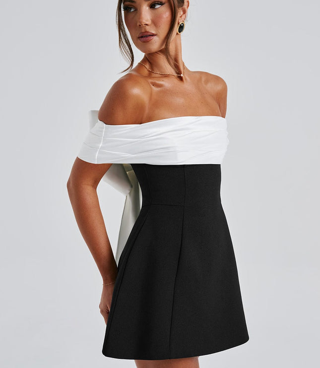 Side view of black cocktail dress with white off shoulder neckline and flared mini skirt