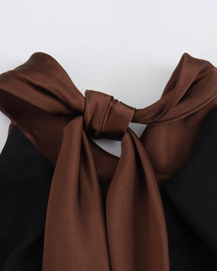 Close-up of satin halter top neckline on brown midi dress with tied straps and soft sheen